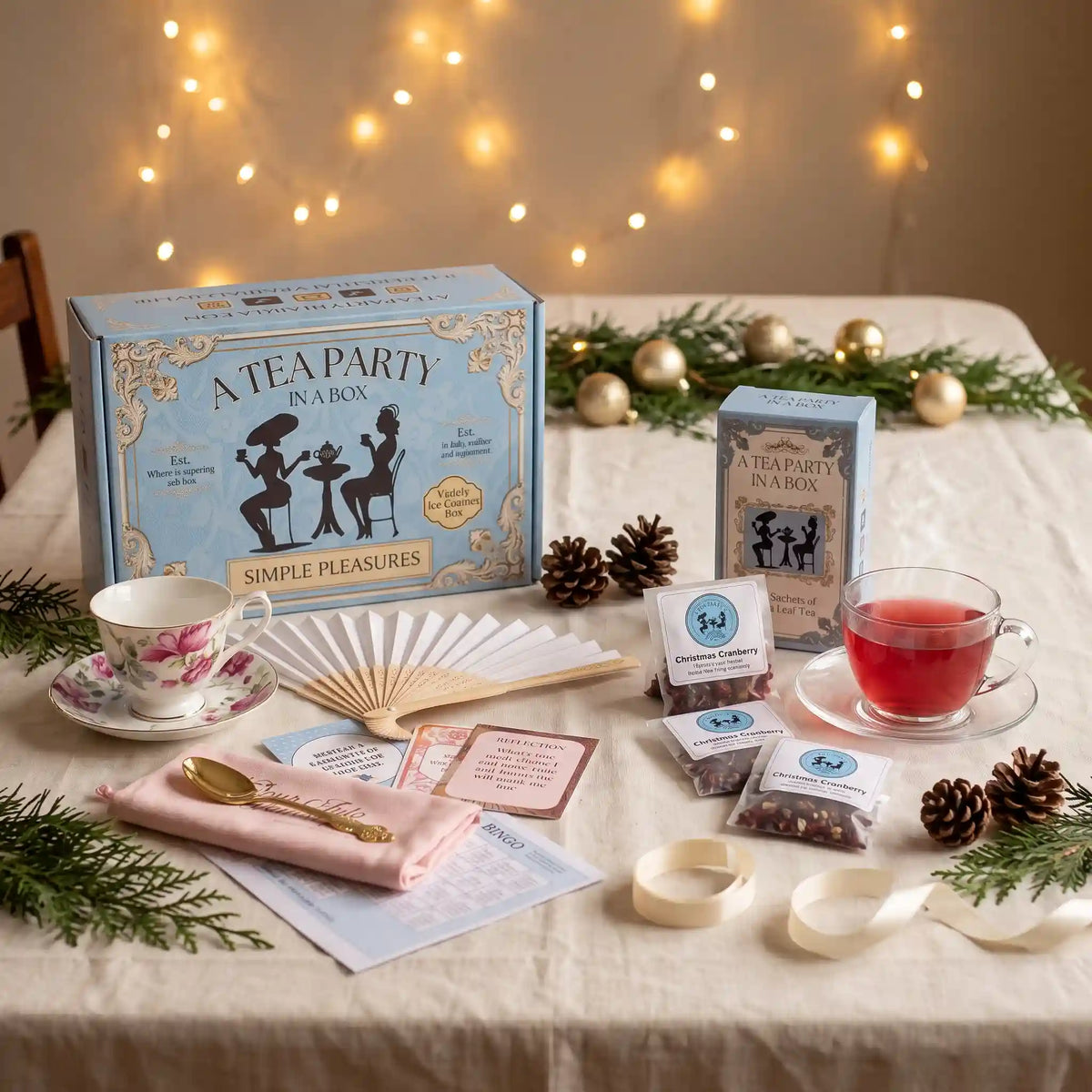 Holiday tea gifts: Simple Pleasures tea party box with a rose teacup beside Christmas Cranberry tea on a festive table