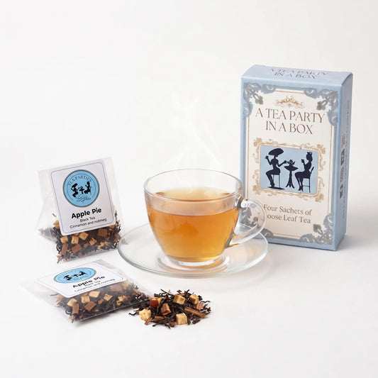 Apple Pie tea brewed in a clear glass teacup beside two labeled loose leaf tea sachets and the A Tea Party In A Box gift box
