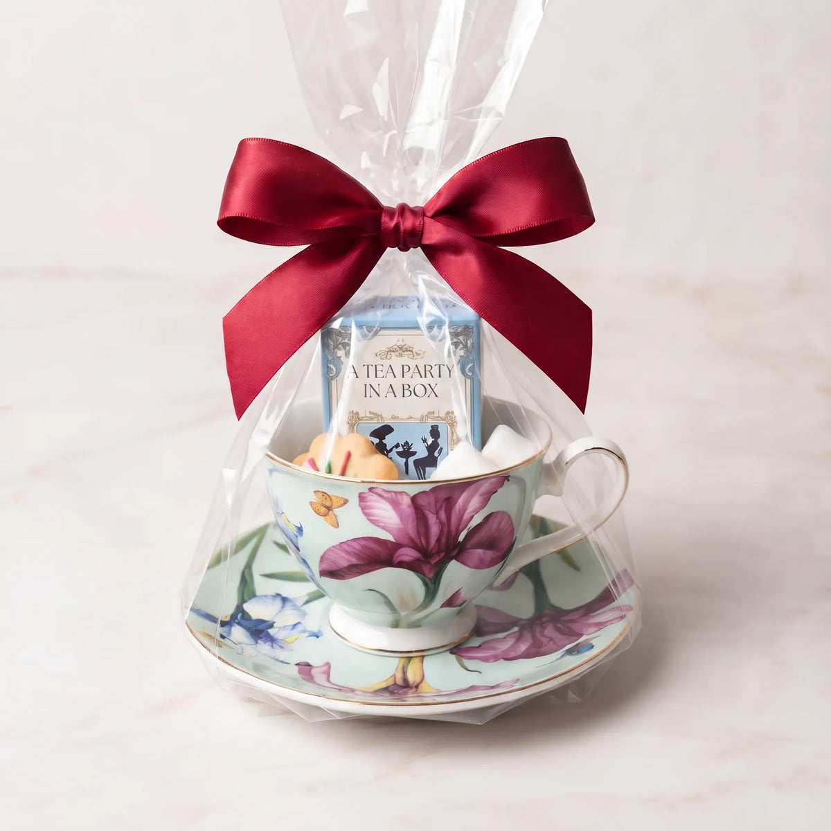 Butterfly Iris teacup and saucer gift set in cellophane with a red bow, tea box, cookie and sugar cubes
