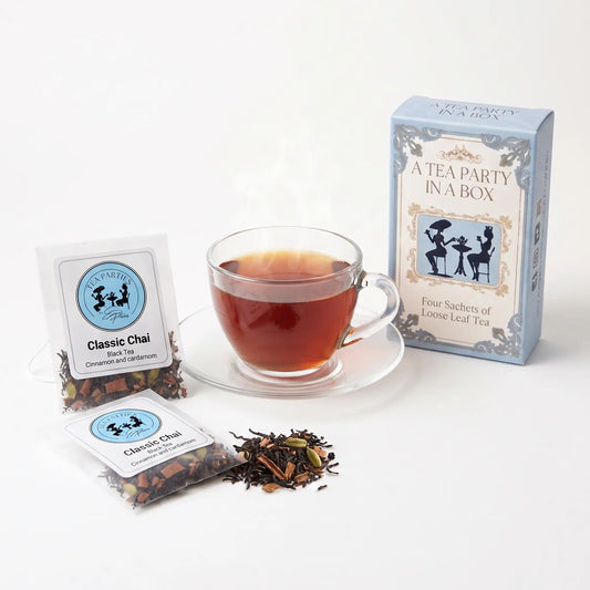 Classic Chai tea brewed in a clear glass teacup beside two labeled loose leaf tea sachets and the A Tea Party In A Box gift box