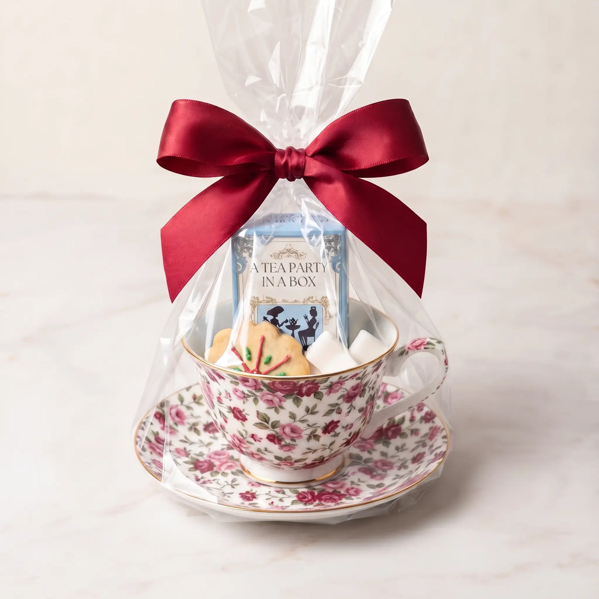 Cottage Bouquet teacup and saucer gift set in cellophane with a red bow, tea box, cookie and sugar cubes