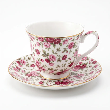 Cottage Bouquet teacup and saucer covered in small pink and deep red roses with green leaves on white, gold-tone rim