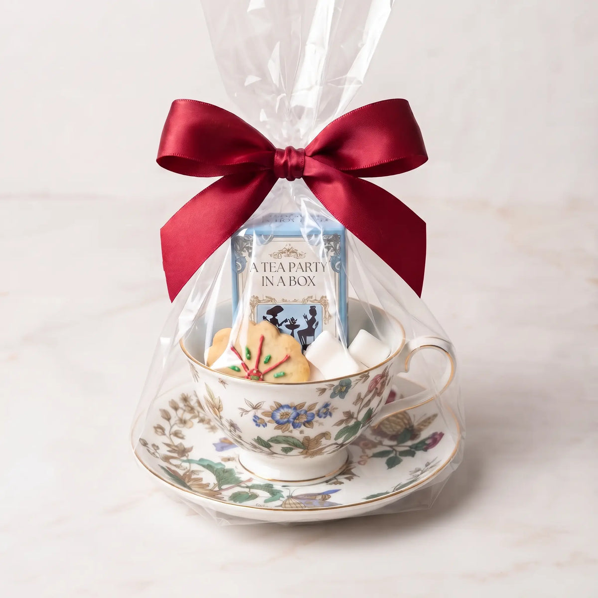 English Floral teacup and saucer gift set in cellophane with a red bow, tea box, cookie and sugar cubes