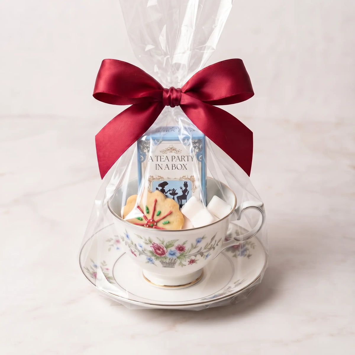 Flower Basket teacup and saucer gift set in cellophane with a red bow, tea box, cookie and sugar cubes