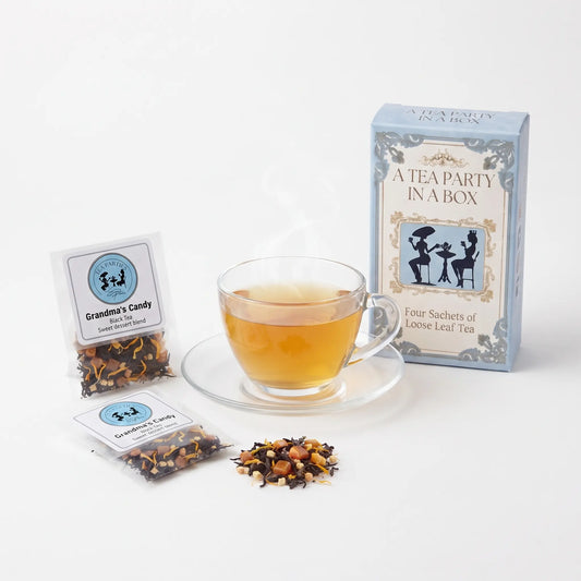Grandma's Candy tea brewed in a clear glass teacup beside two labeled loose leaf tea sachets and the A Tea Party In A Box gift box