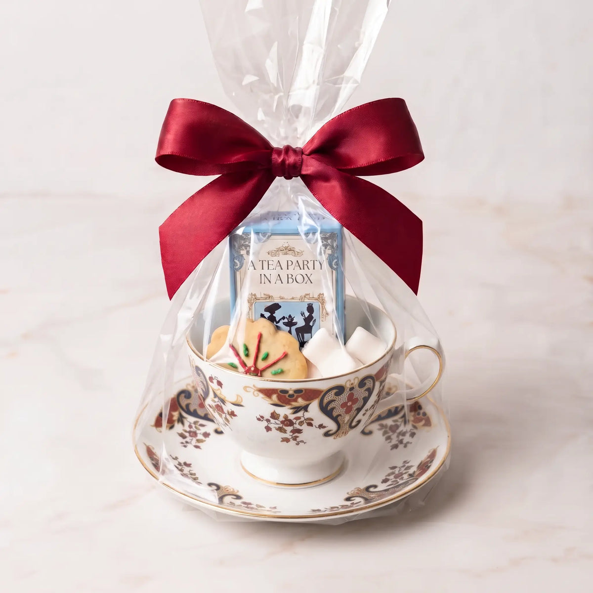 Heirloom Paisley teacup and saucer gift set in cellophane with a red bow, tea box, cookie and sugar cubes