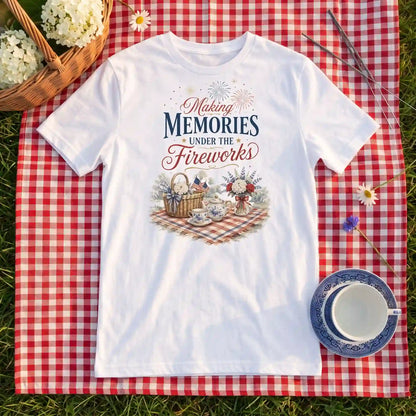 White Making Memories Fourth of July tea party shirt laid flat on a gingham picnic blanket with a teacup
