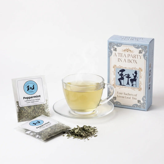Peppermint tea brewed in a clear glass teacup beside two labeled loose leaf tea sachets and the A Tea Party In A Box gift box