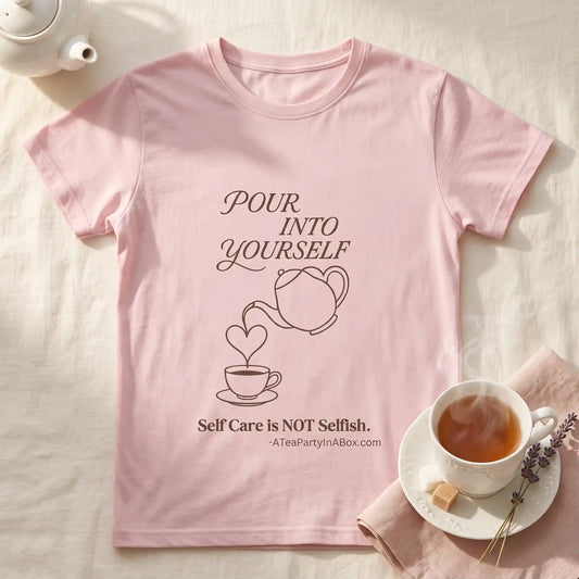 Pink Pour Into Yourself self-care tea shirt laid flat beside a steaming teacup, small teapot, and lavender