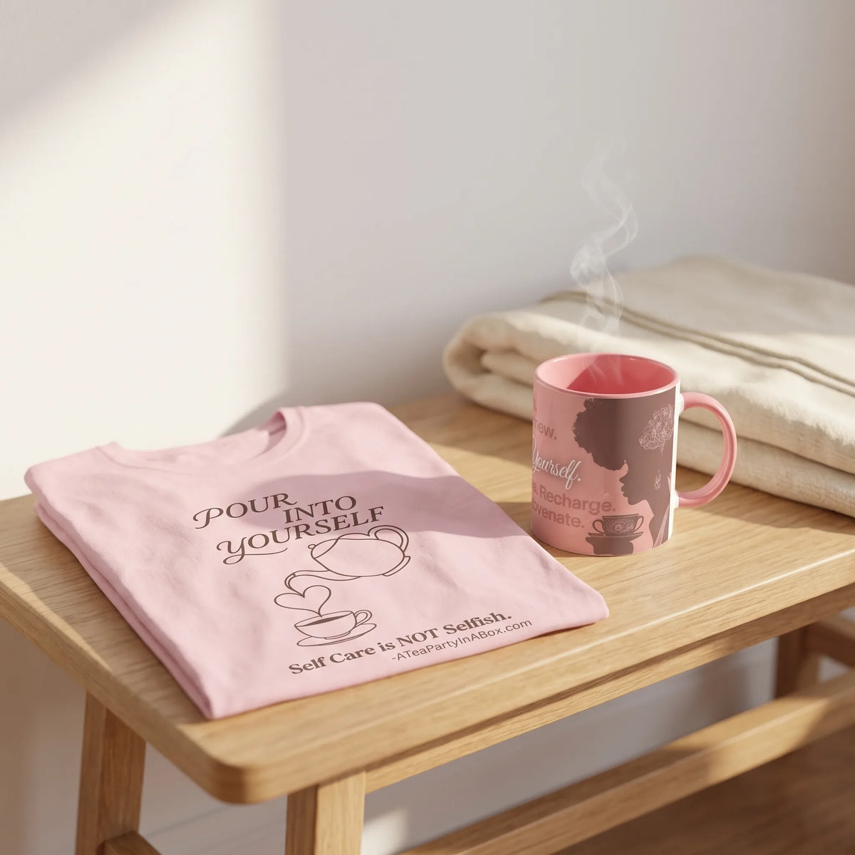 Pour Into Yourself tea shirt laid flat beside the Pink Pour Into Yourself mug on a wooden bench