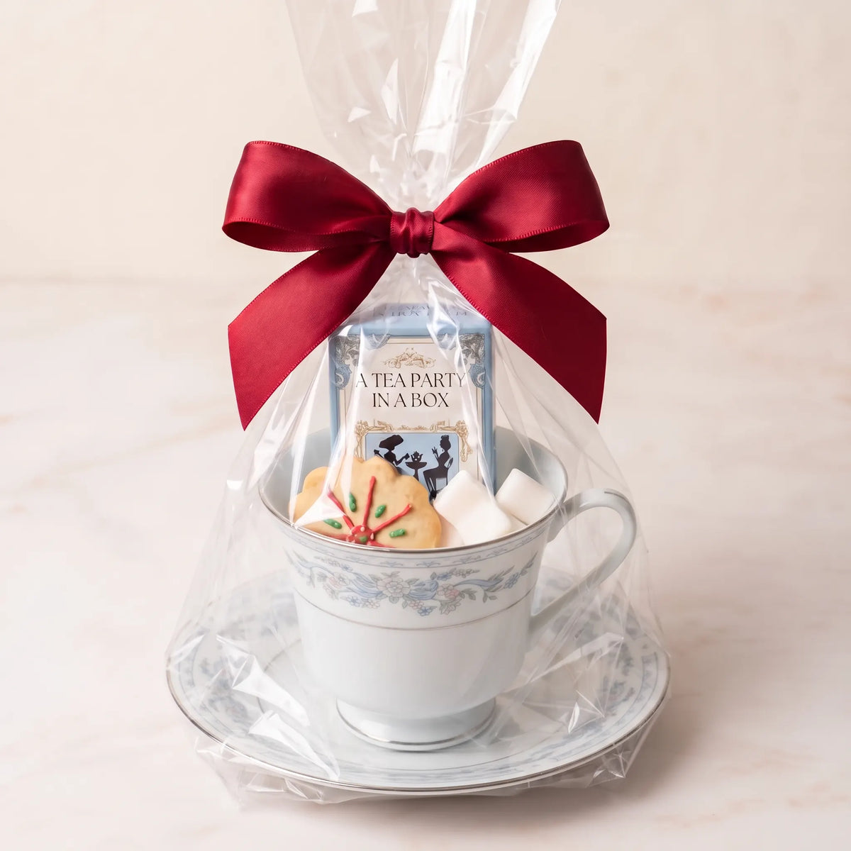 Ribbon Garland teacup and saucer gift set in cellophane with a red bow, tea box, cookie and sugar cubes