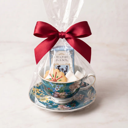 Teal Botanica teacup and saucer gift set in cellophane with a red bow, tea box, cookie and sugar cubes