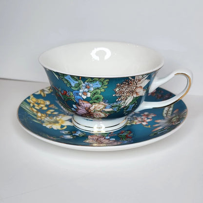 Teal Botanica teacup and saucer with chrysanthemums, lilies, passionflowers and blue blossoms on deep teal, gold-tone rim